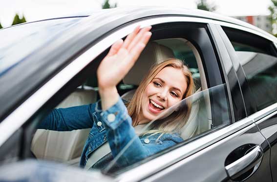 mujer saluda feliz al manejar